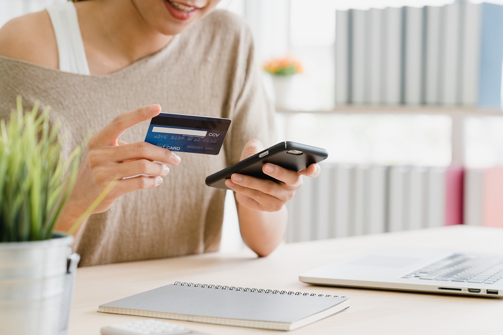 mujer con tarjeta de credito en mano para comprar en sitio web